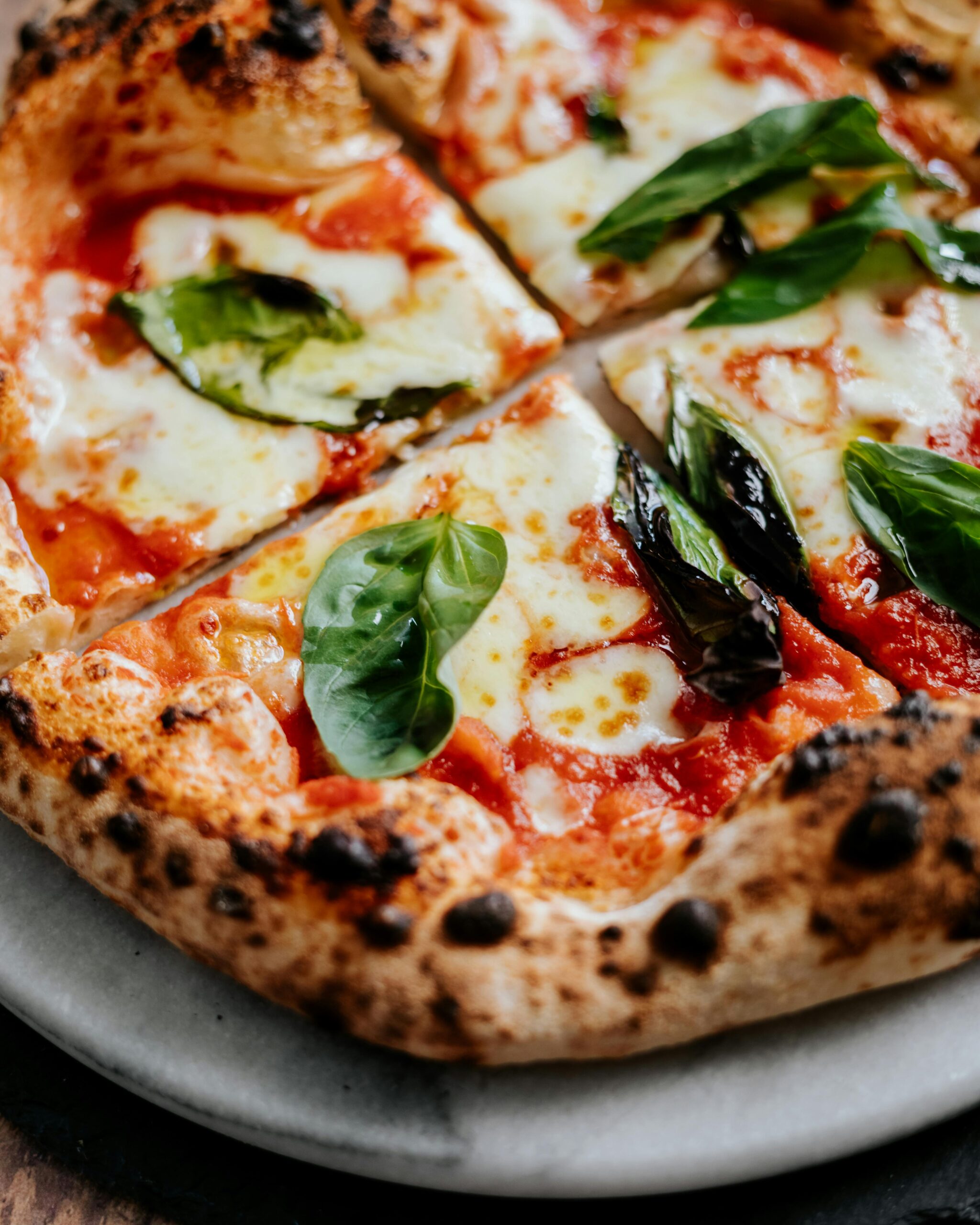 Close-up of a Neapolitan pizza with fresh basil leaves and melted cheese, perfect for food enthusiasts